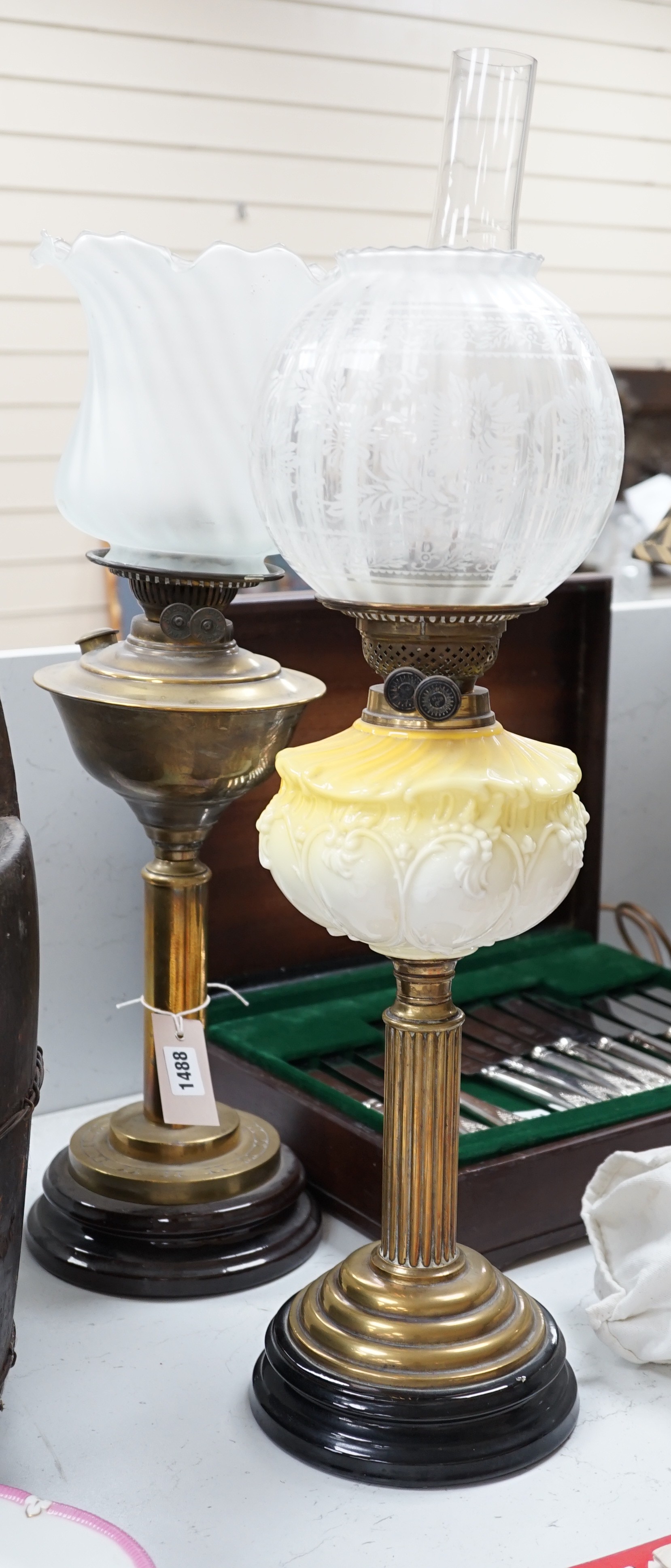 A brass and glass oil lamp and another brass oil lamp, both with shades, tallest 67cms high